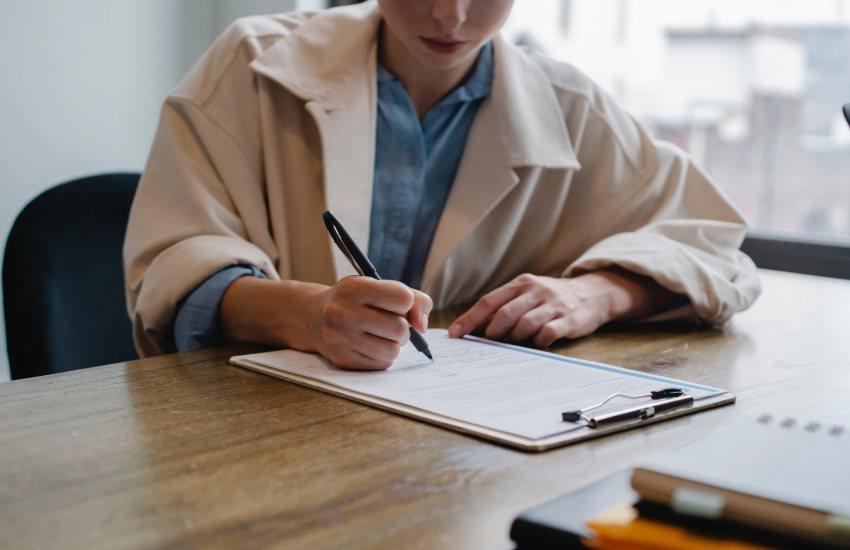 person writing on a clipboard
