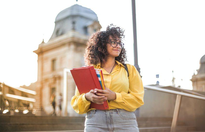 student holding her books outside a university building