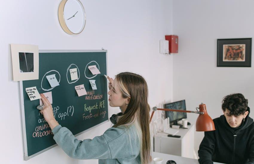 woman putting sticky notes on a chalk board